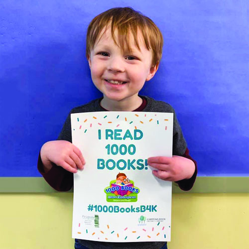 Young boy holding "I read 1000 books sign."