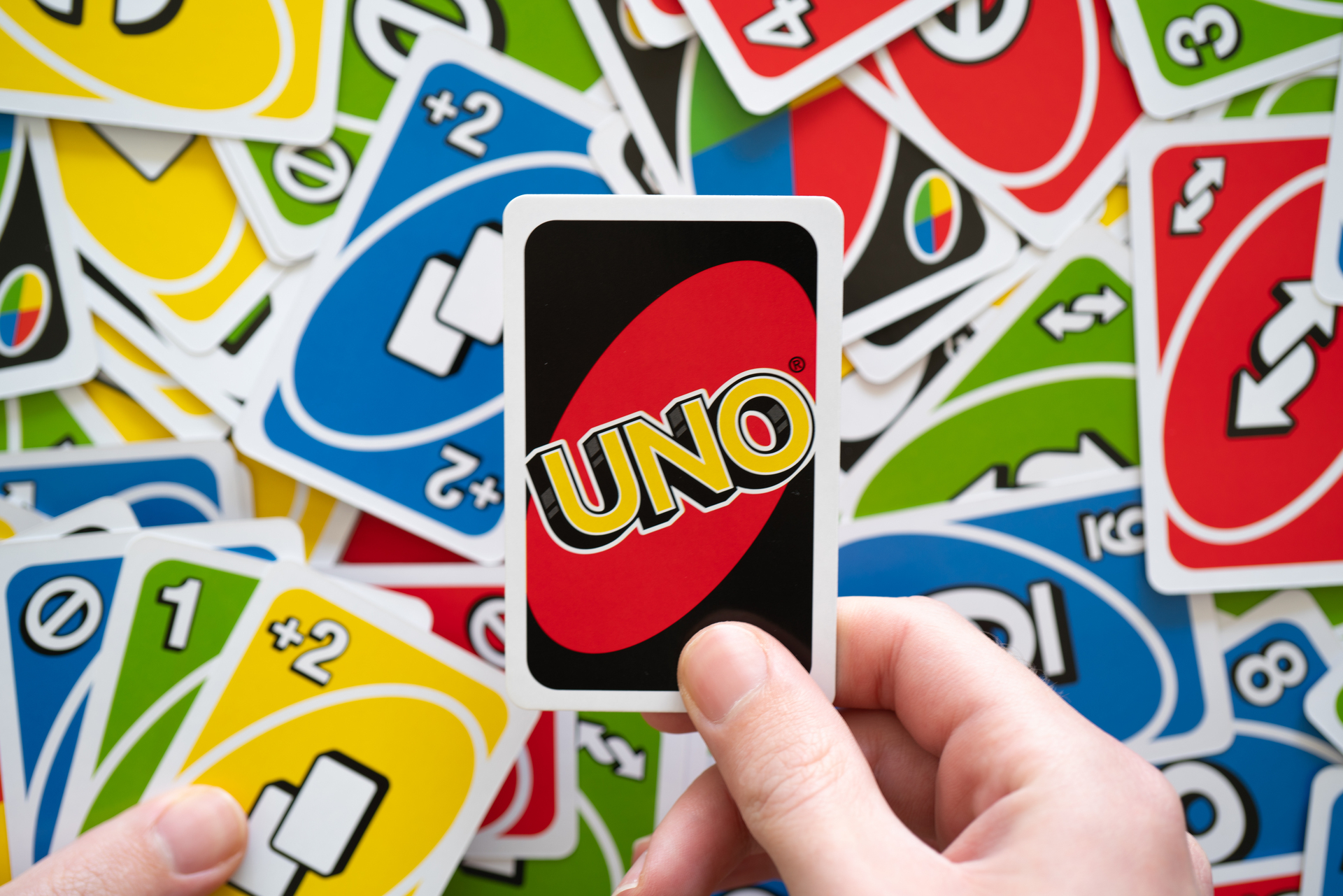 Image of UNO cards on a table with a hand holding one card