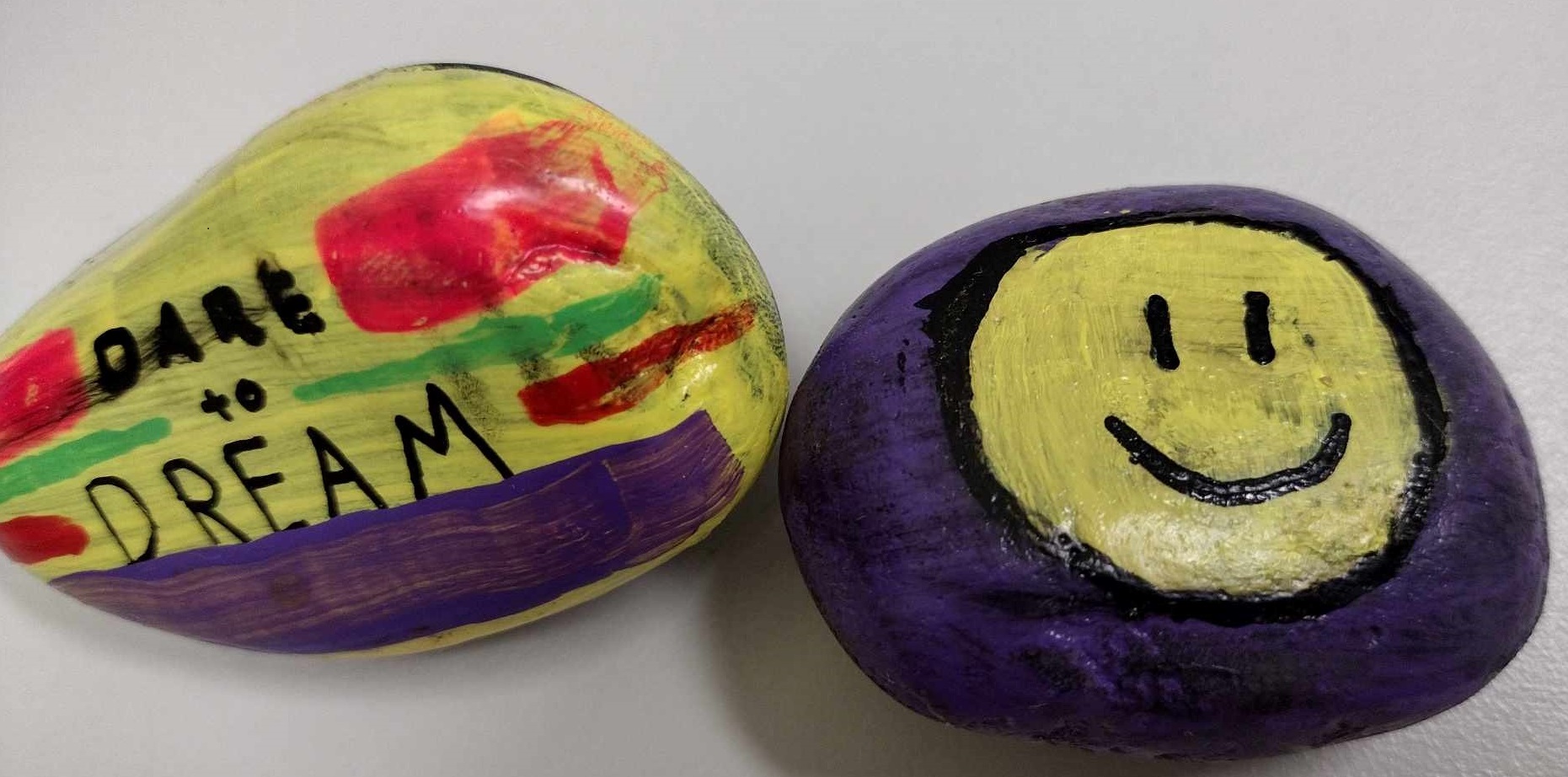 Image of a rock that says "dare to dream" and another rock with a painted a smiley face.