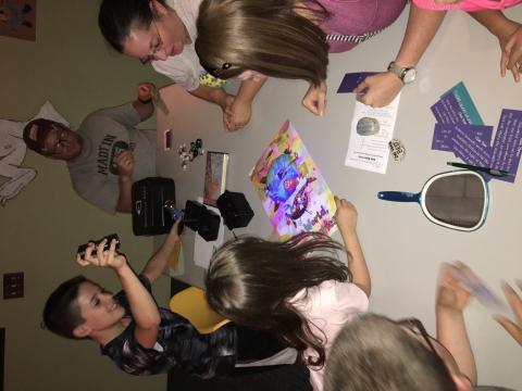 Image of children using UV flashlight solving clues in a breakout room.