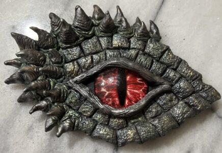 Image of a dragon eye made of clay with a red iris.